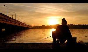 Рыболов на рыбалке на закате